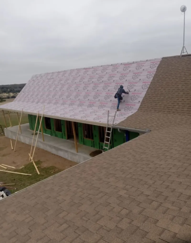 Worker preparing underlayment for a metal roof installation in Independence